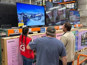 Shoppers consider a large-screen television with the help of a sales associate in a Costco warehouse Thursday, May 1, 2025, in Sheridan, Colo.
