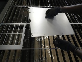 FILE - A worker lifts a steel sheet after cutting it in a specific design at a factory in a suburb of Bengaluru, India, Feb. 27, 2025.