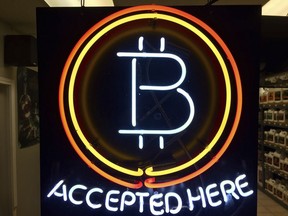 FILE - A neon sign that alerts customers that the business accepts bitcoin as payment, hangs in the window of Healthy Harvest Indoor Gardening in Hillsboro, Ore., on Feb. 7, 2018.