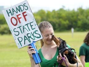 FILE - Bonnie, a seven-month-old dachshund, licks Alexandra Maxwell's face as they a protest against Gov. Ron DeSantis' plan to develop state parks with business ventures such as golf courses, pickleball courts and large hotels, during a demonstration at Oleta River State Park, Aug. 27, 2024, in North Miami Beach, Fla.