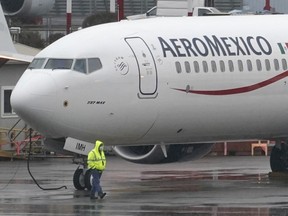 FILE - A worker wearing a mask walks past a Boeing 737 Max 9 as it is prepared for a flight from Renton Municipal Airport, Nov. 18, 2020, in Renton, Wash.