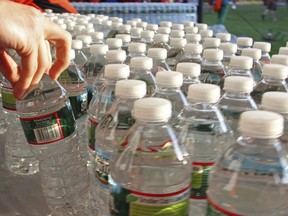 FILE - A runner grabs a bottle of water at the athlete's village prior to the start of the 116th running of the Boston Marathon, in Hopkinton, Mass., April 16, 2012.