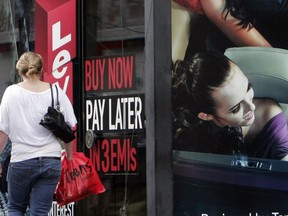 FILE - A woman walks by a sign