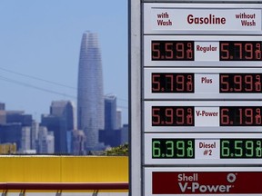 FILE - The Salesforce Tower and skyline are shown behind the gasoline price board at a gas station in San Francisco, July 20, 2022.