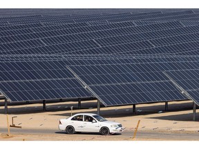 A car travels past photovoltaic panels at the Al Dhafra Solar project, constructed by Electricite de France SA (EDF) and Jinko Power Technology Co. Ltd., in Abu Dhabi, United Arab Emirates, on Tuesday, Jan 31, 2023. During a visit to the site French Economy Minister Bruno Le Maire said to journalists