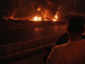 A man looks at flames rising from an oil storage facility after it was hit by an Israeli strike in Tehran, Iran, June 15.