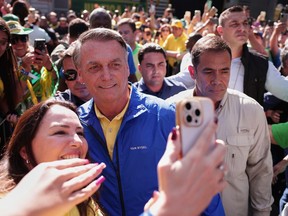Former President Jair Bolsonaro poses for a selfie with a supporter upon arriving at a protest against his Supreme Court trial, in which he is accused of involvement in a 2022 coup attempt, in Sao Paulo, Sunday, June, 29, 2025.