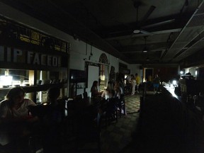 FILE - Customers sit inside a restaurant lit by battery-powered lanterns during an island-wide power outage, in Old San Juan, Puerto Rico, April 16, 2025.