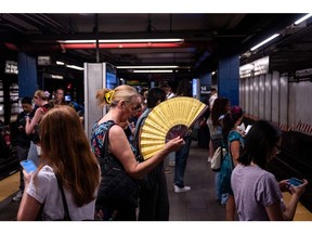 A commuter uses a hand fan at the 14th Street-Union Square subway station in New York.