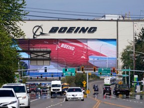 FILE - Traffic drives in view of a Boeing Co. production plant, where images of jets decorate the hangar doors on April 23, 2021, in Everett, Wash.