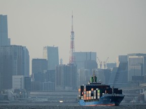 Tokyo Tower is seen amid tall buildings as a container ship leaves a cargo terminal in Tokyo, Wednesday, April 9, 2025.