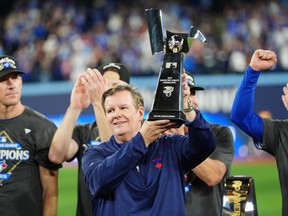 Edward S. Rogers III, chairman of the board of directors of Rogers Communications, holds the American League Championship Series trophy as the Blue Jays celebrate after defeating the Seattle Mariners in MLB American League Championship Series game 7 baseball action in Toronto, Monday, Oct. 20, 2025.