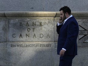 A man speaks on the phone as he walks past the Bank of Canada in Ottawa on Wednesday, Sept. 17, 2025. THE CANADIAN PRESS/