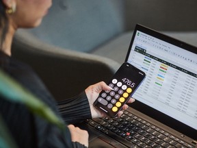 A person uses the calculator app on their phone and works on a spreadsheet in a photo illustration made in Toronto, on Monday, Sept. 22, 2025.