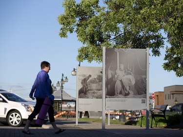 A pedestrian passes historic photographs of an aluminum factory in the town of Arvida in Saguenay, Que.