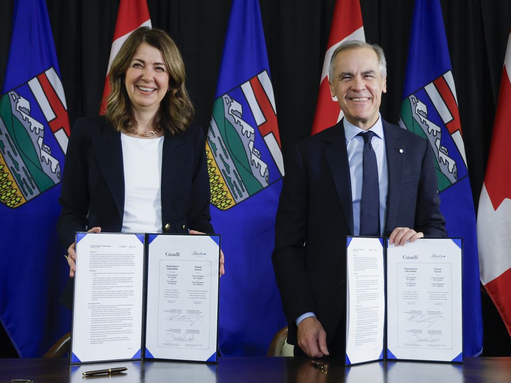 Prime Minister Mark Carney, right, signs an MOU with Alberta Premier Danielle Smith in Calgary, Alta. on Nov. 27, 2025.