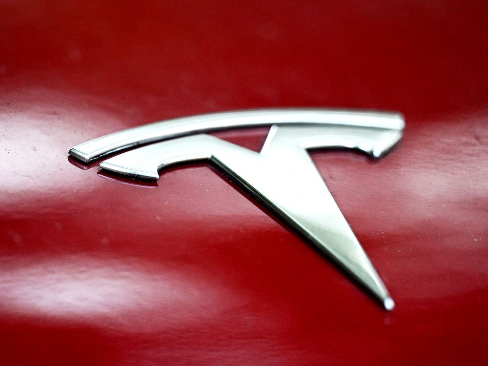 This photograph taken on October 23, 2025 shows a Tesla logo on the body of car parked in Warsaw.