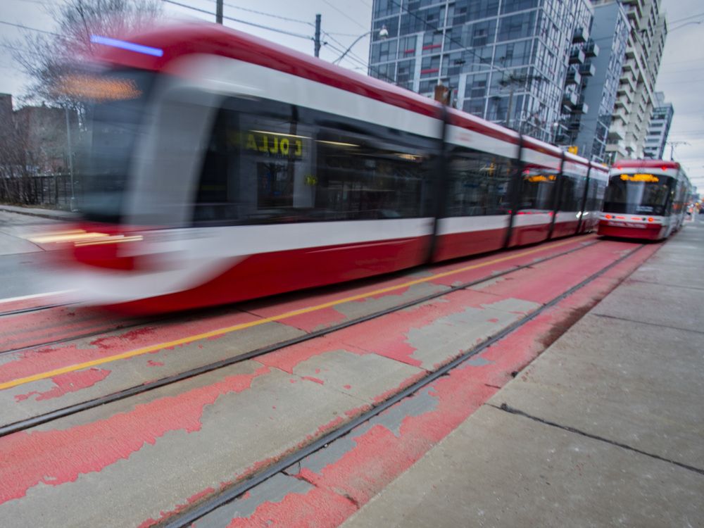A TTC streetcar passes by the peeling red paint on the RapidTO surface transit lanes along Bathurst St., near Front St., in downtown Toronto on December 25, 2025.