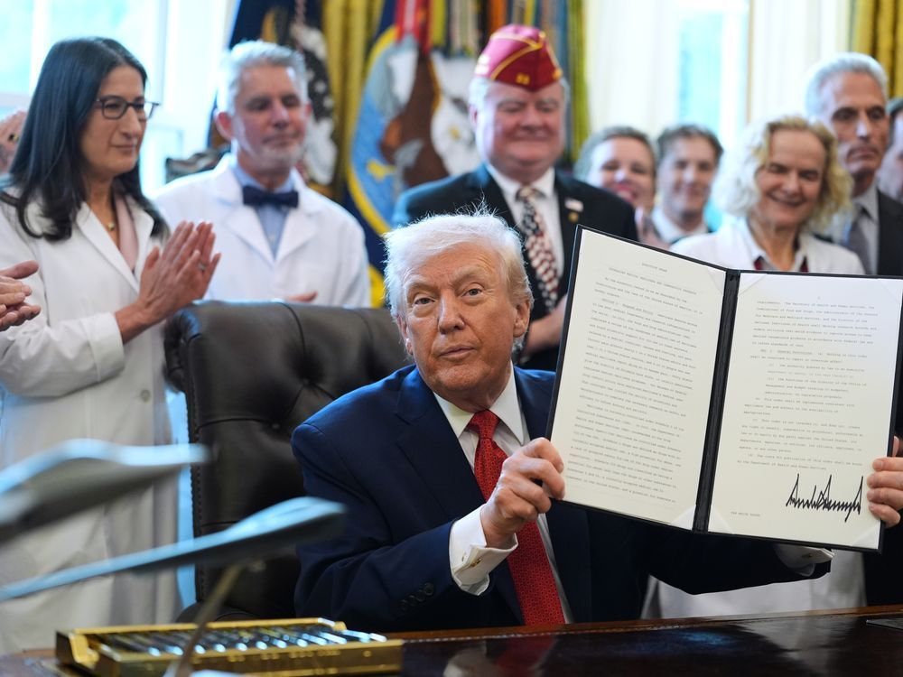 President Donald Trump displays an executive order reclassifying marijuana as a less dangerous drug in the Oval Office of the White House, Thursday, Dec. 18, 2025, in Washington.