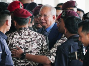 FILE - Malaysian former Prime Minister Najib Razak, center, is escorted by prison officers on his arrival at the Kuala Lumpur High Court complex in Kuala Lumpur, Malaysia, Oct. 30, 2024.