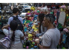 Shoppers pass by a street vendor hawking stuffed toys in Caracas.