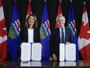 Prime Minister Mark Carney, right, signs a memorandum of understanding with Alberta Premier Danielle Smith in Calgary on Nov. 27.