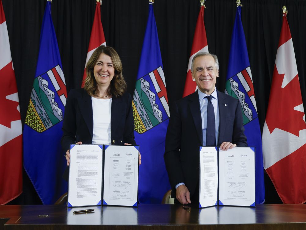 Prime Minister Mark Carney, right, signs a memorandum of understanding with Alberta Premier Danielle Smith in Calgary, Alta., on Nov. 27.