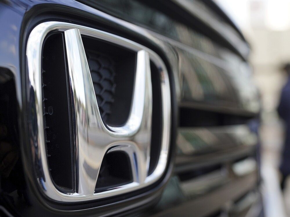 People walk near the logo of Honda Motor Company at a showroom in Tokyo, Feb. 8, 2022.