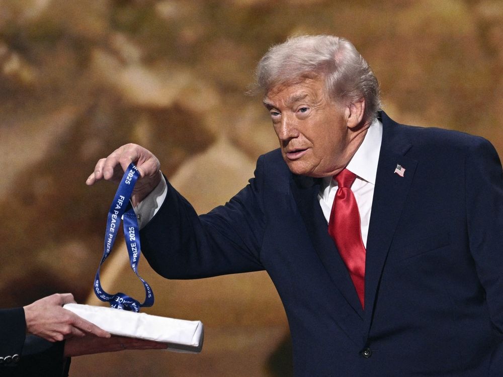 Trump holds his medal as he receives the FIFA Peace Prize from FIFA President Gianni Infantino.