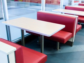 An empty booth style table at a fast food restaurant, white top and red seats