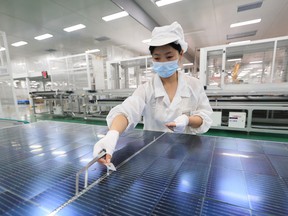 An employee works on photovoltaic cell modules, used in solar panels, at a factory which produces the modules for export to the US and Europe, in Lianyungang.