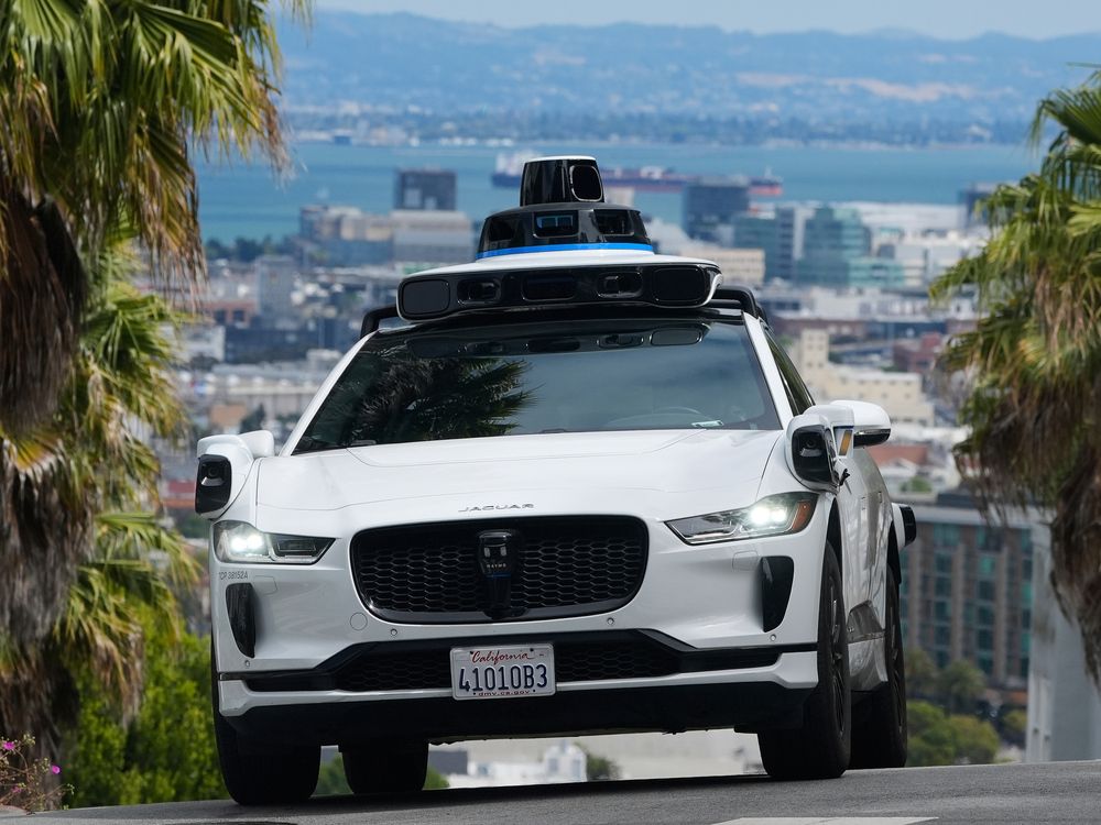 A Waymo car drives up a hill in San Francisco