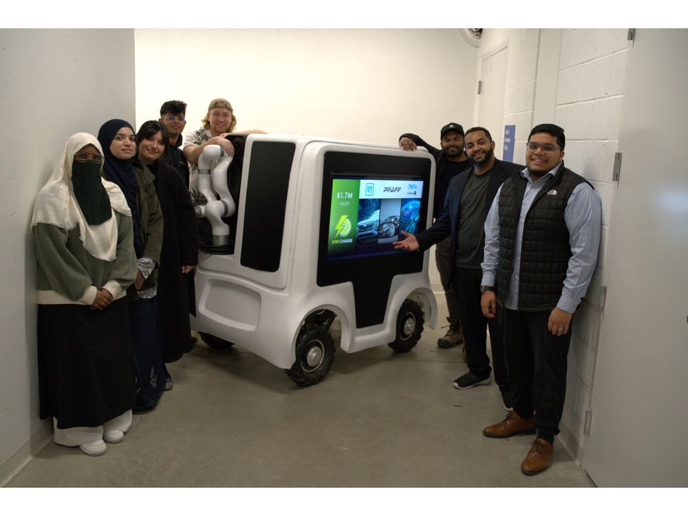 Version 2 of the Kiwi Charge Robot, pictured with the team