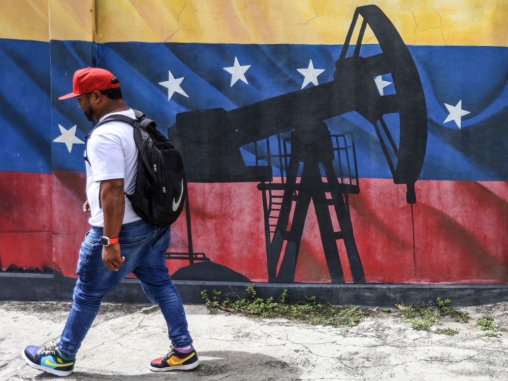 A man walks past a mural depicting an oil pumpjack on a Venezuelan flag in Caracas on January 15, 2026.