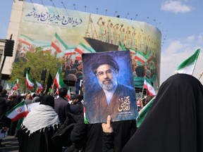 A mourner holds a picture depicting Iran's supreme leader Mojtaba Khamenei during the funeral of Iran's security chief Ali Larijani and Gholamreza Soleimani, a senior officer in the Islamic Revolutionary Guard Corps who commands Basij forces, in Tehran on March 18, 2026.