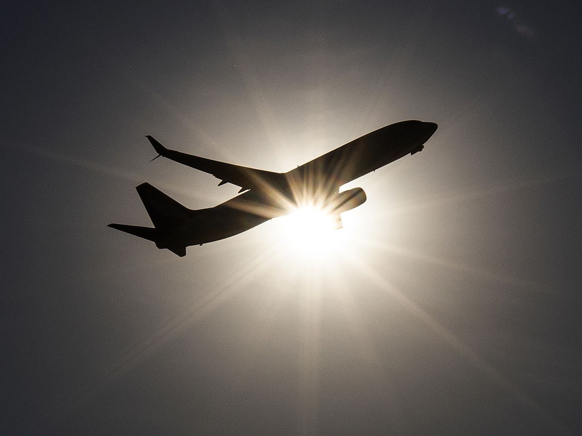 A plane flies past the sun on take off from Toronto Pearson International Airport, Tuesday July 22, 2025.