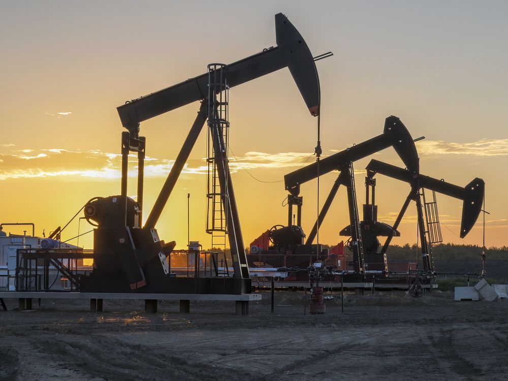 Three oil well pumpjacks at sunrise near Crossfield, Alberta.