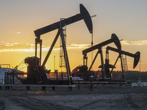 Three oil well pumpjacks at sunrise near Crossfield, Alberta.