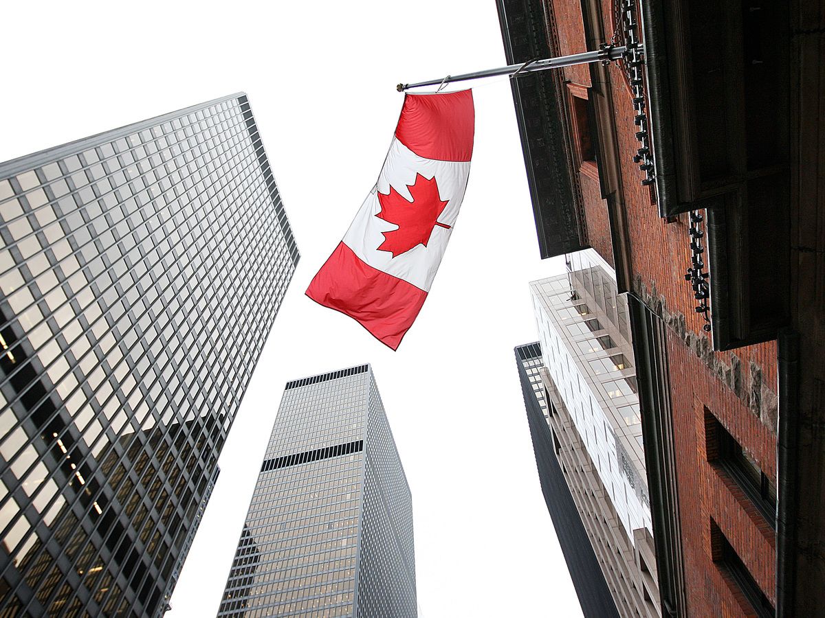 A Canadian flags flies over Toronto's financial district among the towering big bank towers.
