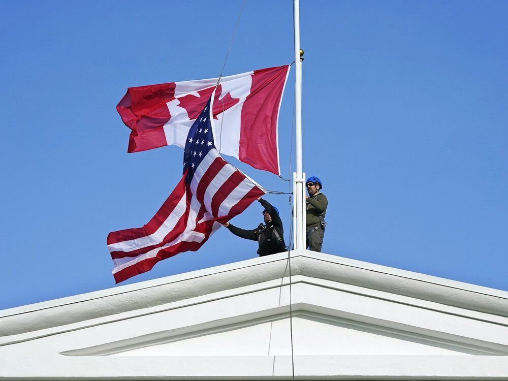 Washington State Park workers Casey Matheson, left, and Zac Carsten put up a new American flag in front of a Canadian flag they just replaced during scheduled maintenance atop the Peace Arch in Peace Arch Historical State Park Monday, Nov. 8, 2021, in Blaine, Wash.