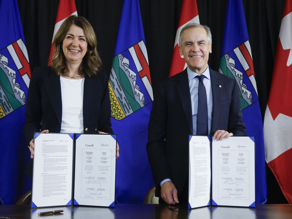 Prime Minister Mark Carney, right, signs an MOU with Alberta Premier Danielle Smith in Calgary, Alta. on Nov. 27, 2025.