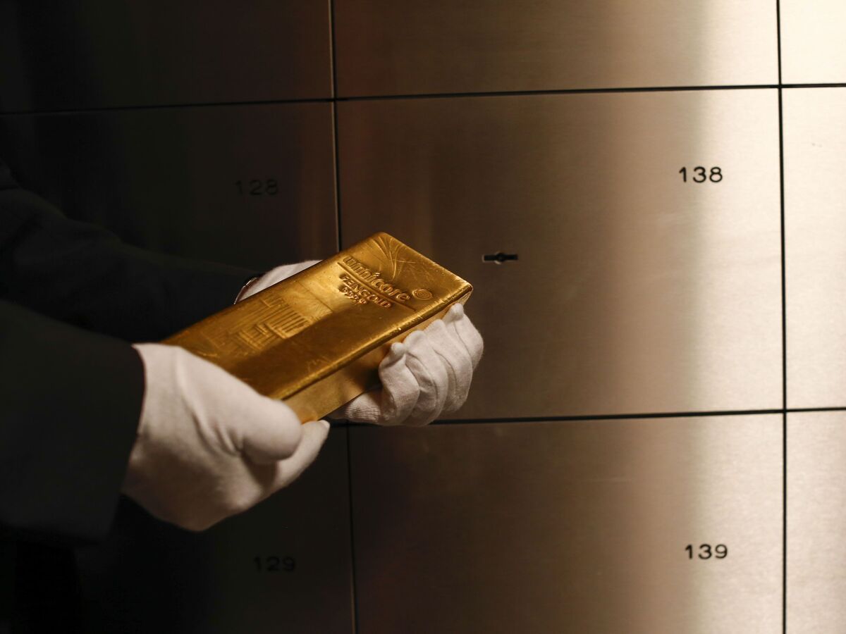 An employee holds a gold bar weighing 12.5 kilograms in the precious metals vault at Pro Aurum KG in Munich, Germany, on Wednesday, July 10, 2019.