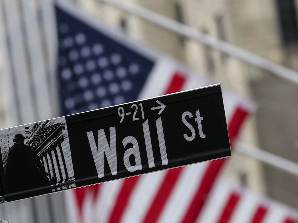 The American flag flies behind a Wall Street sign near the New York Stock Exchange (NYSE) in New York City on April 22, 2026