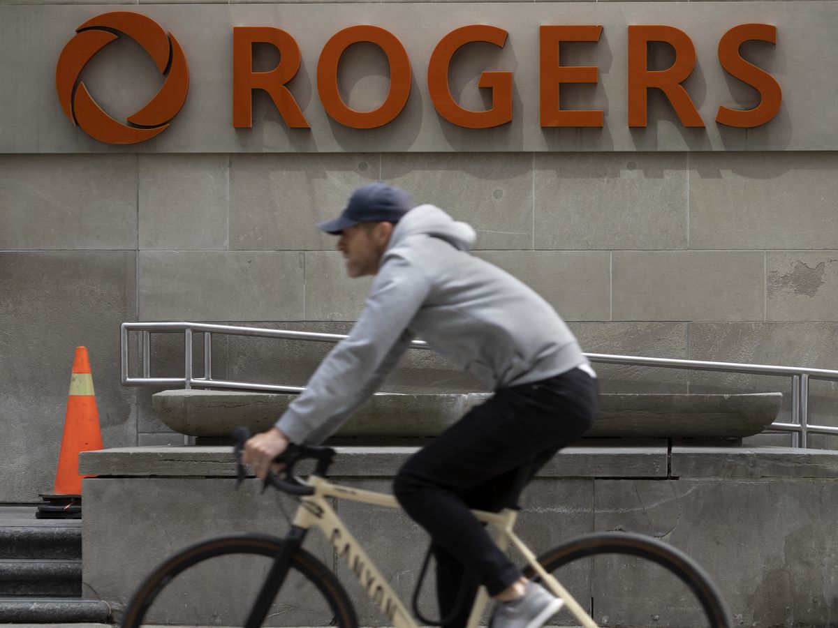A cyclist rides past Rogers Communications Inc. signage on Toronto's Bloor Street.