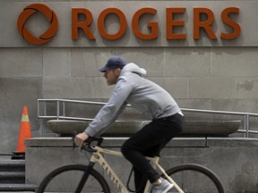 A cyclist rides past Rogers Communications Inc. signage on Toronto's Bloor Street.