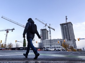 A pedestrian walks across Bloor Street West at Kipling Avenue in front of multiple condominium buildings under construction in Toronto, Monday November 10, 2025.