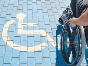 unrecognizable handicapped man in a wheelchair passing over blue and white handicapped sign painted on the floor