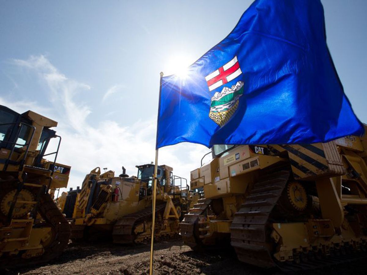 An Alberta provincial flag is surrounded by pipeline heavy machinery in Edmonton.