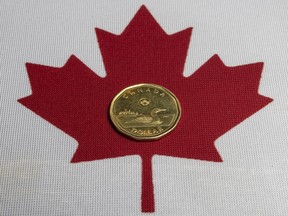 The Canadian loonie dollar and Canadian flag, Wednesday March 5, 2025.