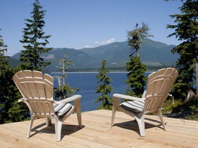 Two adirondack chairs on a deck, lakeside
